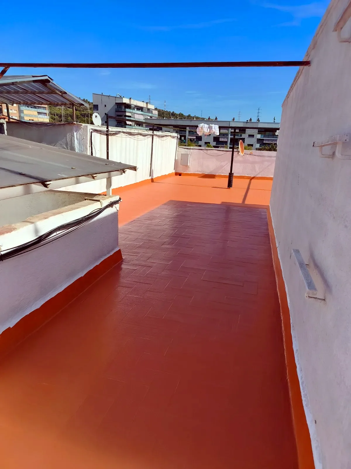 Terraza larga impermeabilizada en rojo junto a la barandilla